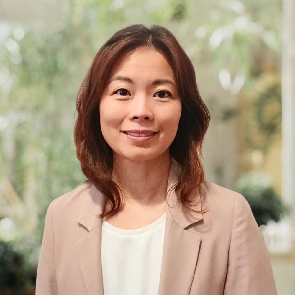 A woman wearing a white shirt and blazer, exuding professionalism.
