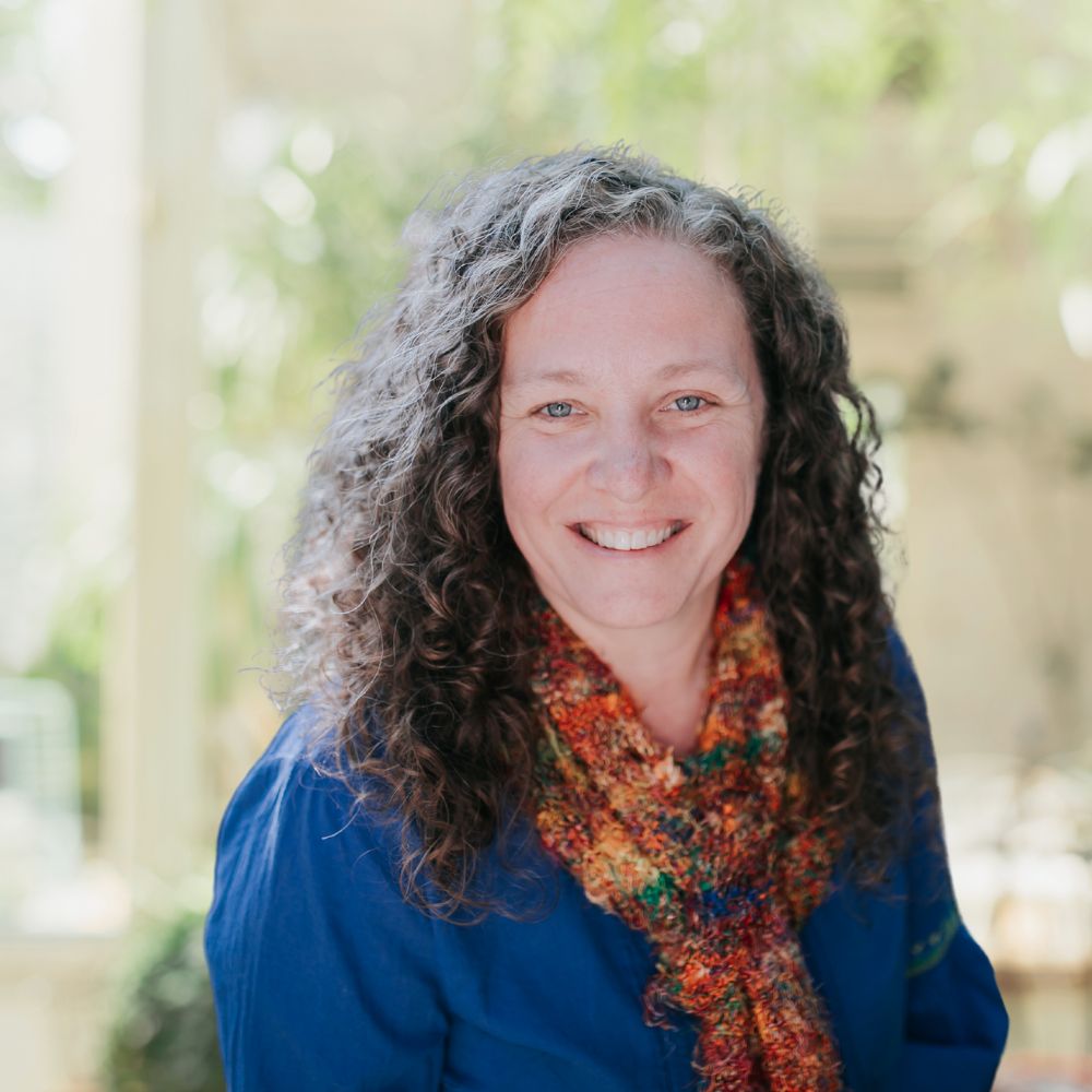 A woman with curly hair and a blue shirt, exuding confidence and style.