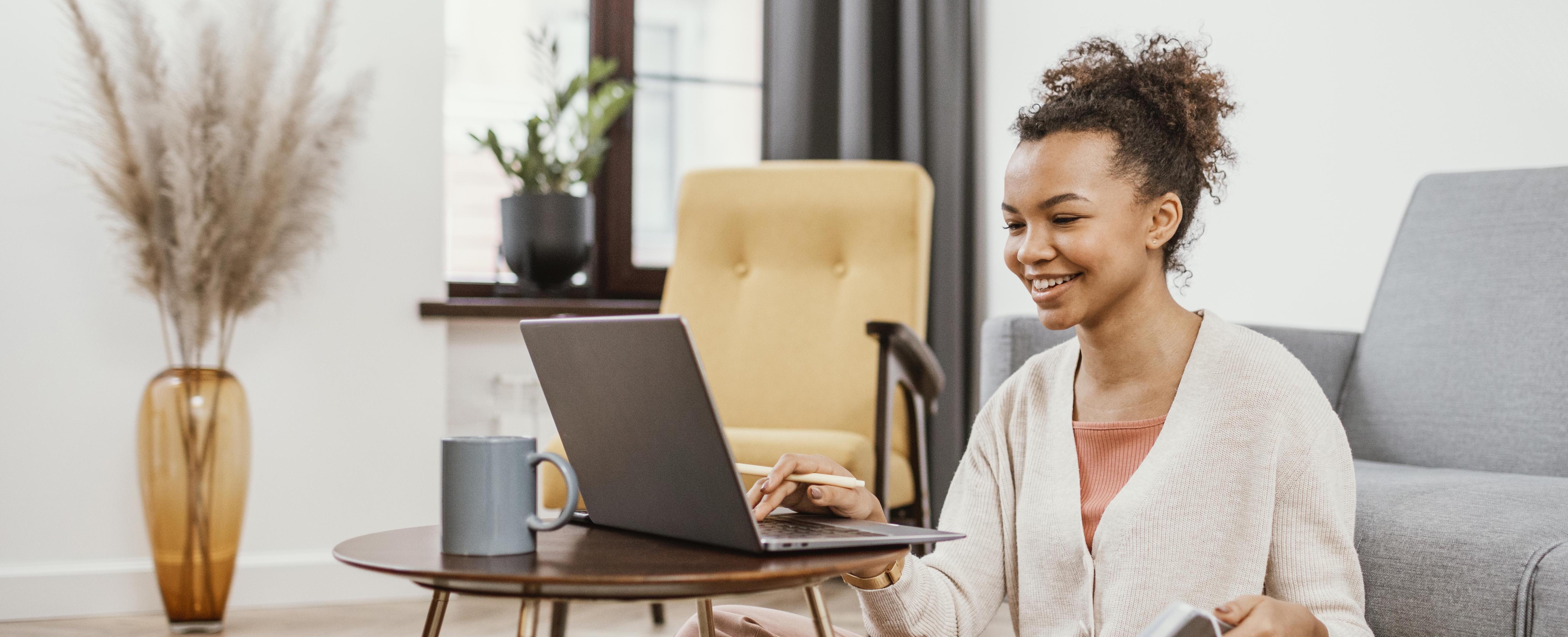 A woman with a cheerful expression, using her laptop, fully engaged in her tasks.