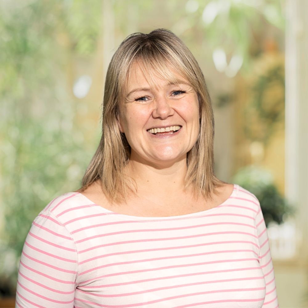 A woman wearing a pink and white striped shirt, looking stylish and confident.