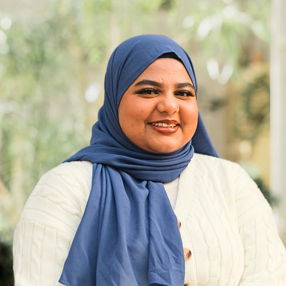 A woman wearing a blue hijab and white sweater, exuding elegance and modesty in her attire.