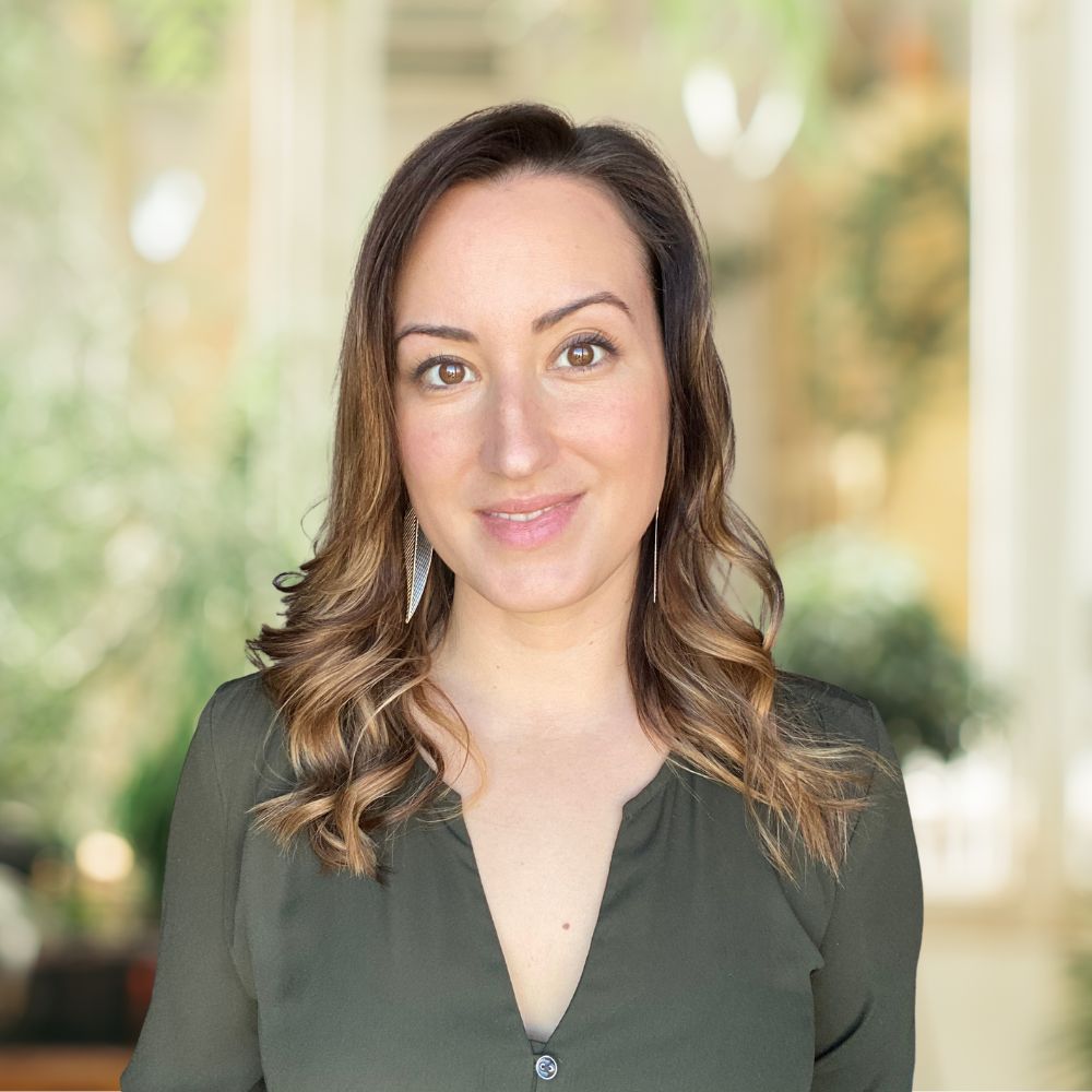 A woman with long and wavy hair wearing a green shirt.