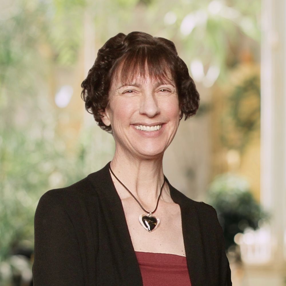 A woman with short hair and a red top smiling, radiating warmth and happiness.