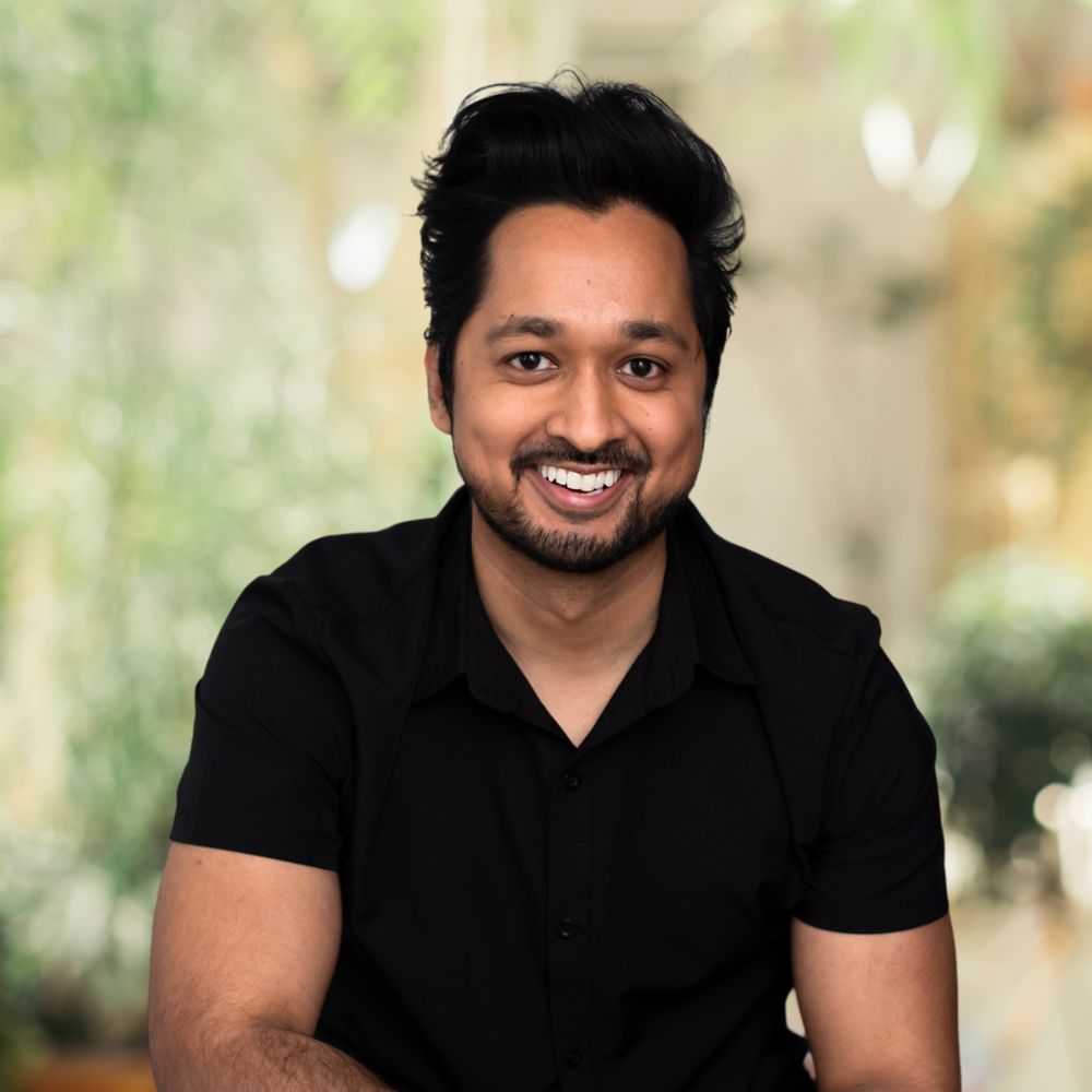 A man in a black shirt smiling for the camera.