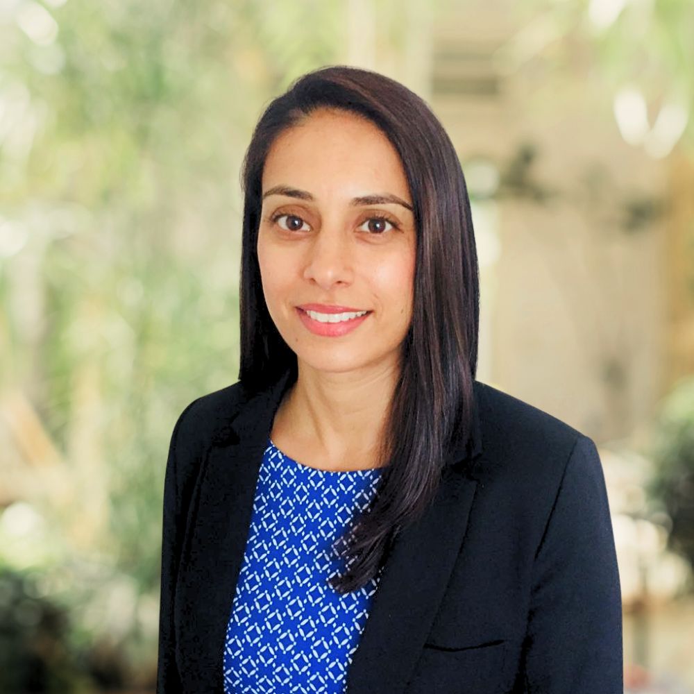 A professional woman wearing a blue and white shirt, and a black blazer.