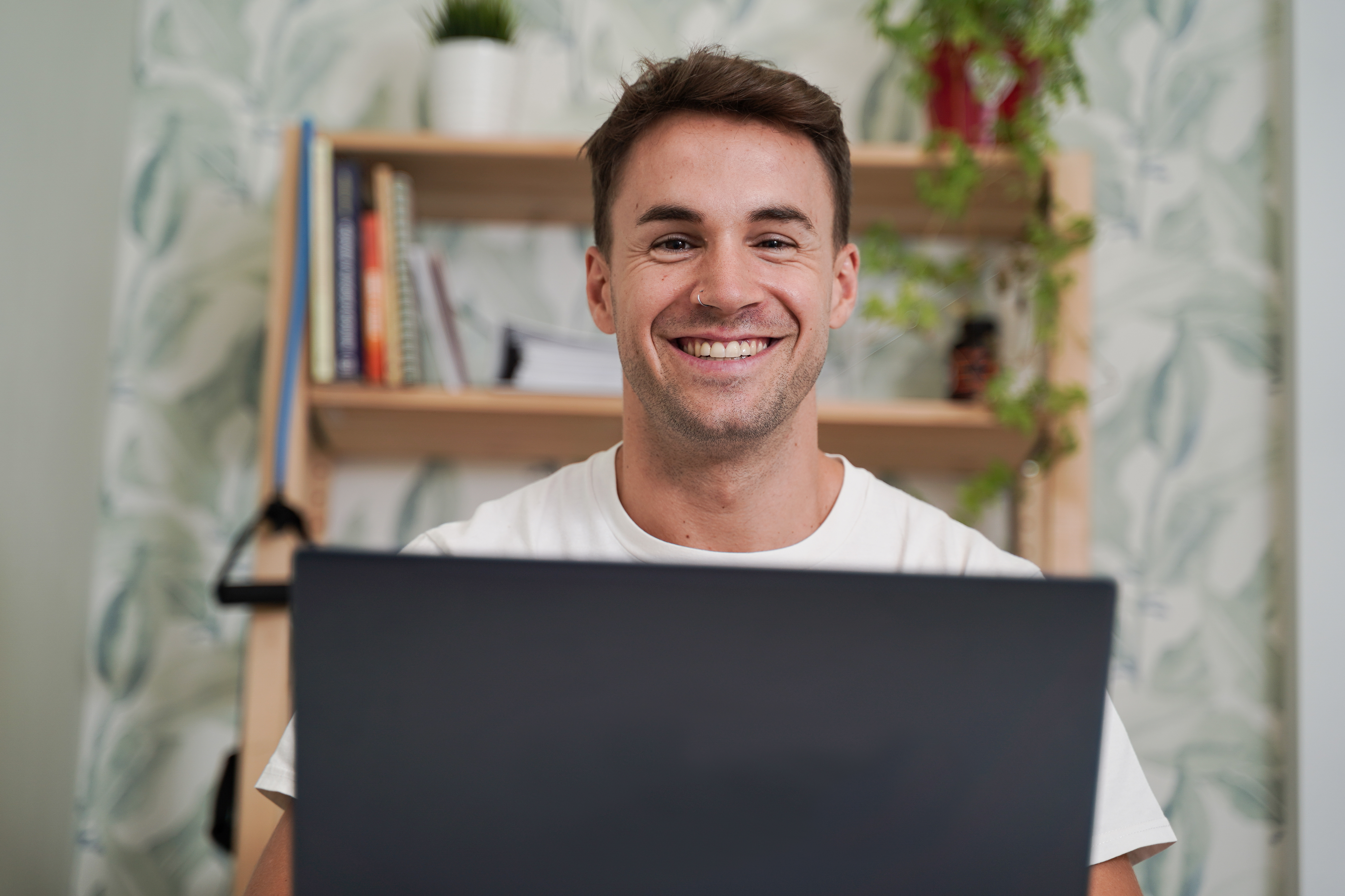 A man smiling while using a laptop at home.
